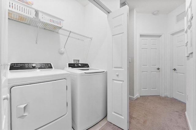 laundry room featuring separate washer and dryer and light colored carpet