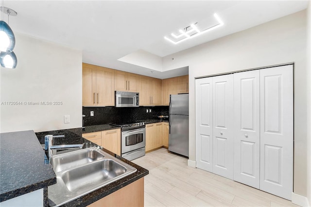 kitchen featuring stainless steel appliances, pendant lighting, light brown cabinets, sink, and backsplash