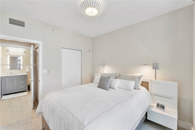 bedroom featuring a closet, light hardwood / wood-style flooring, and connected bathroom