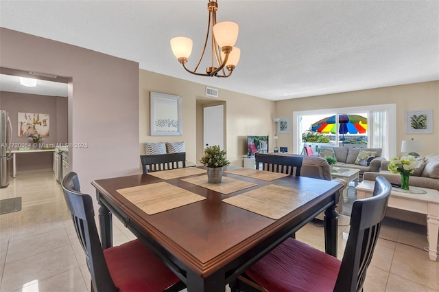 dining area featuring a chandelier, a textured ceiling, and light tile patterned flooring