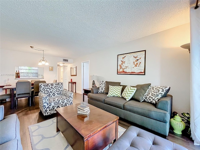 living room featuring hardwood / wood-style floors, a textured ceiling, and an inviting chandelier