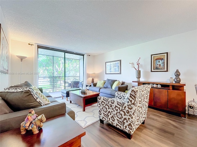 living room with light hardwood / wood-style floors, a wall of windows, and a textured ceiling