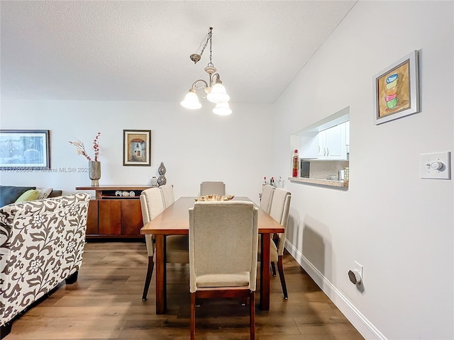 dining area with dark hardwood / wood-style floors, a textured ceiling, and a chandelier