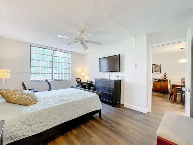 bedroom with ceiling fan, wood-type flooring, and a textured ceiling