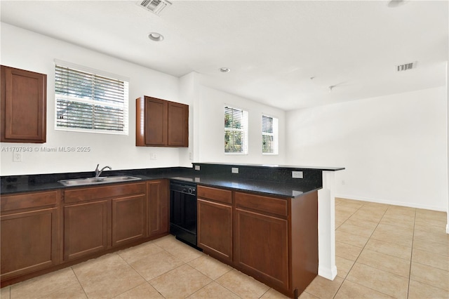 kitchen with kitchen peninsula, sink, light tile patterned floors, and black dishwasher