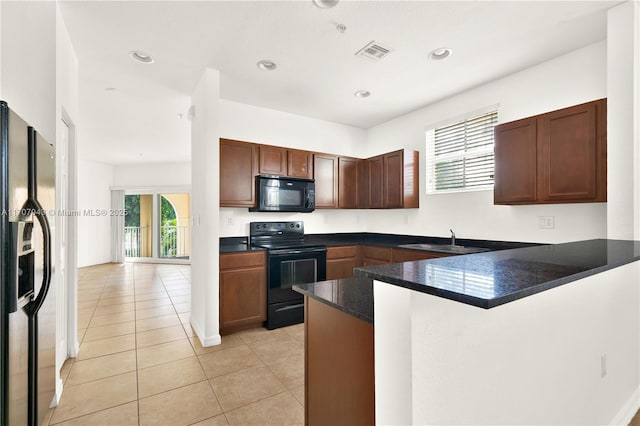 kitchen featuring sink, kitchen peninsula, dark stone countertops, light tile patterned floors, and black appliances