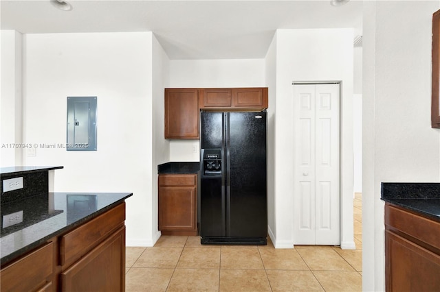 kitchen with electric panel, black refrigerator with ice dispenser, light tile patterned flooring, and dark stone counters