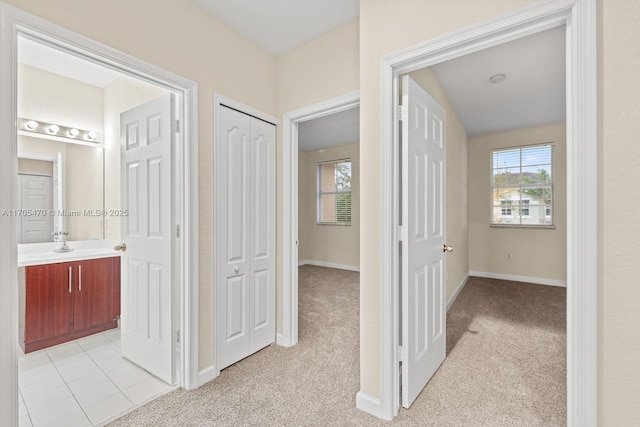 hallway featuring light carpet, sink, and a healthy amount of sunlight