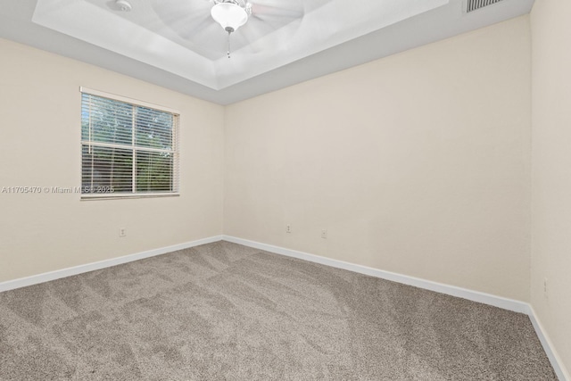 carpeted empty room featuring a tray ceiling