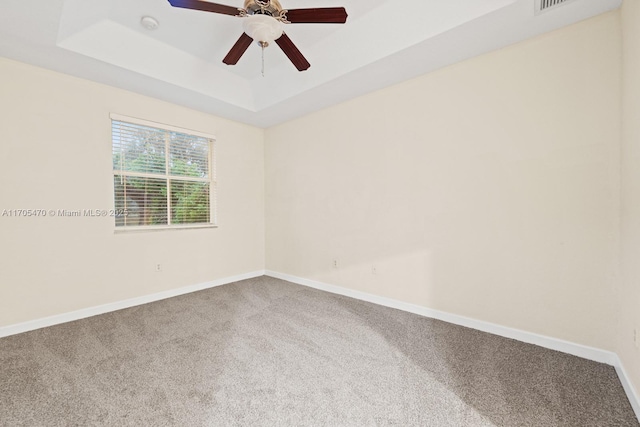 spare room featuring carpet floors, a tray ceiling, and ceiling fan