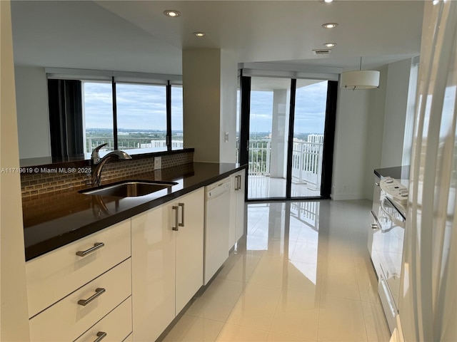 kitchen featuring white cabinetry, sink, tasteful backsplash, white dishwasher, and light tile patterned floors