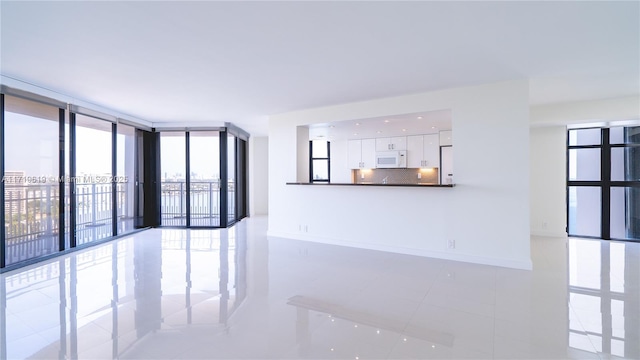 empty room featuring floor to ceiling windows and baseboards