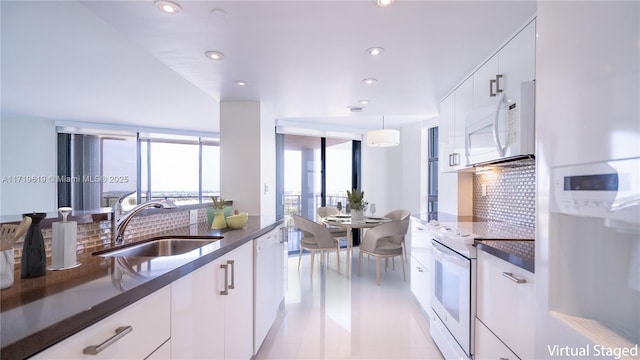 kitchen with white appliances, decorative backsplash, white cabinetry, a sink, and recessed lighting