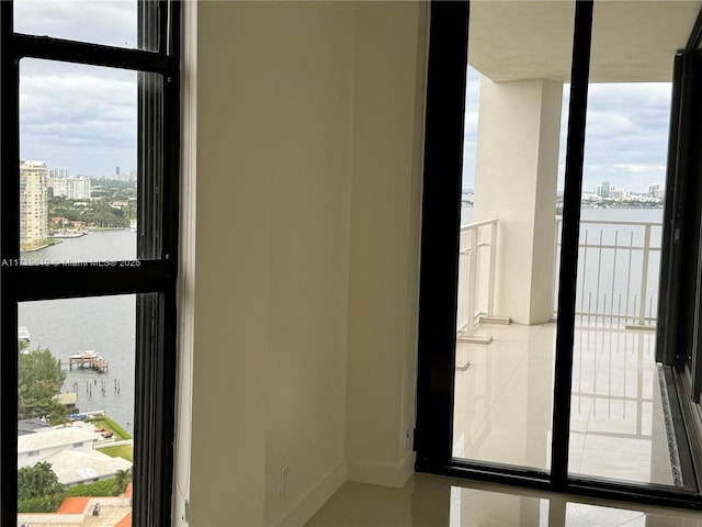 doorway with a water view, baseboards, floor to ceiling windows, and a city view