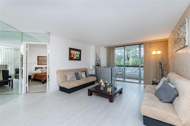 living room with hardwood / wood-style flooring, a textured ceiling, and a wall of windows