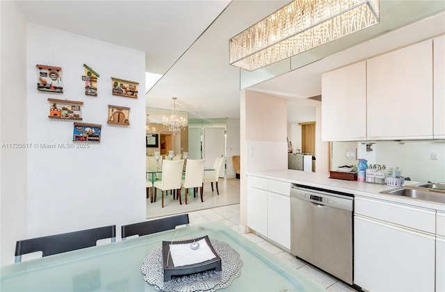 kitchen featuring stainless steel dishwasher, white cabinets, sink, and hanging light fixtures