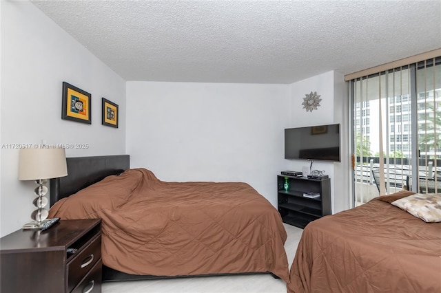 bedroom with access to exterior, a textured ceiling, and a wall of windows