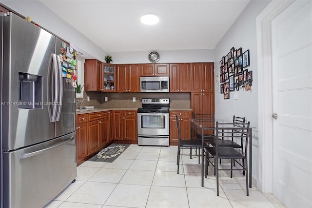 kitchen featuring decorative backsplash, light tile patterned floors, and stainless steel appliances