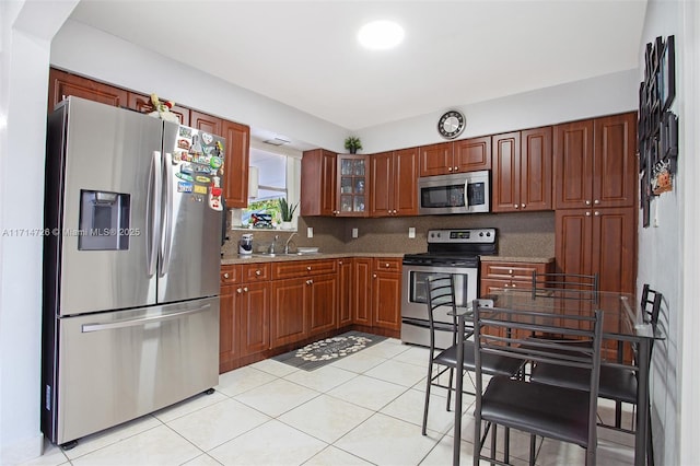 kitchen featuring sink, stainless steel appliances, tasteful backsplash, light stone counters, and light tile patterned flooring