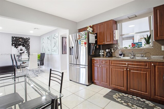 kitchen featuring decorative backsplash, stainless steel fridge with ice dispenser, light tile patterned floors, and sink