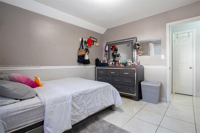 tiled bedroom featuring vaulted ceiling