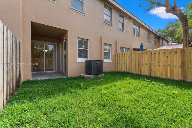 rear view of property with a lawn and cooling unit