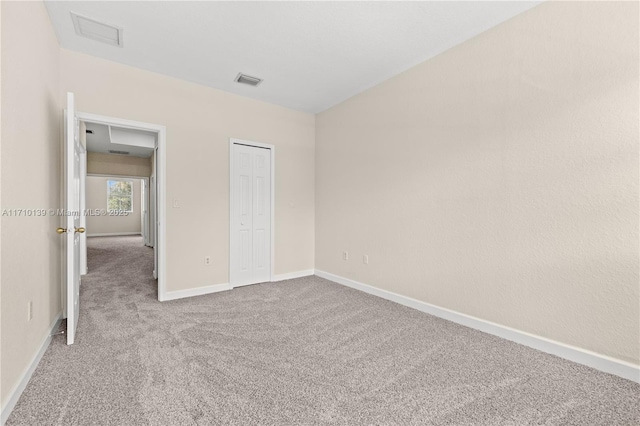 unfurnished bedroom with light colored carpet and a closet