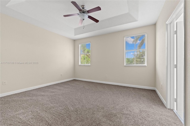 spare room featuring carpet flooring, a raised ceiling, and ceiling fan