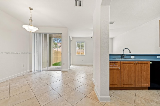 kitchen featuring dishwasher, sink, light tile patterned flooring, and hanging light fixtures