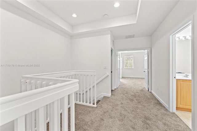 corridor with carpet floors and a tray ceiling