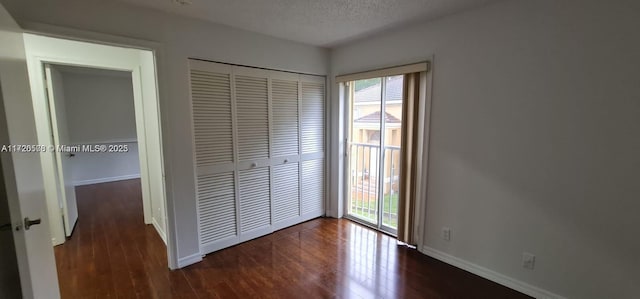 unfurnished bedroom with dark hardwood / wood-style flooring, a textured ceiling, and a closet