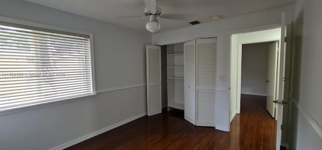 unfurnished bedroom with a closet, dark wood-type flooring, and ceiling fan