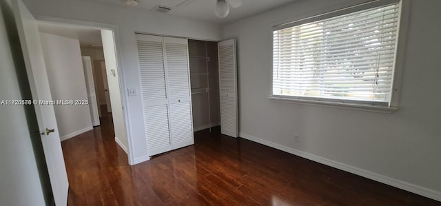 unfurnished bedroom with ceiling fan, a closet, and dark wood-type flooring