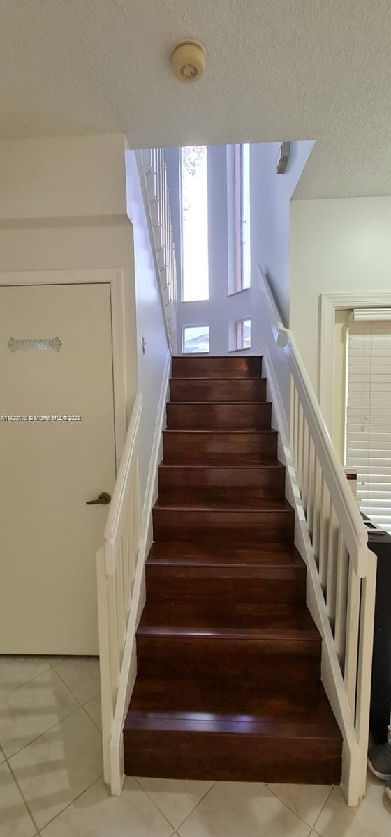 stairs with tile patterned floors and a textured ceiling