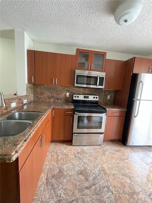 kitchen featuring stone counters, sink, stainless steel appliances, tasteful backsplash, and a textured ceiling