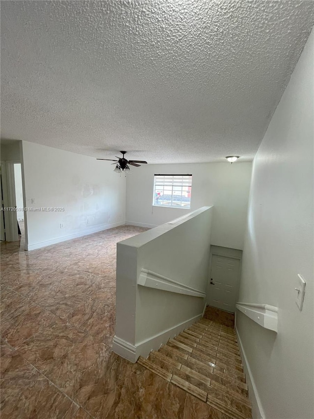 staircase featuring ceiling fan and a textured ceiling