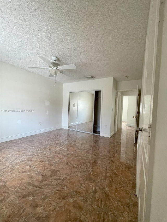 unfurnished bedroom with a textured ceiling, a closet, and ceiling fan