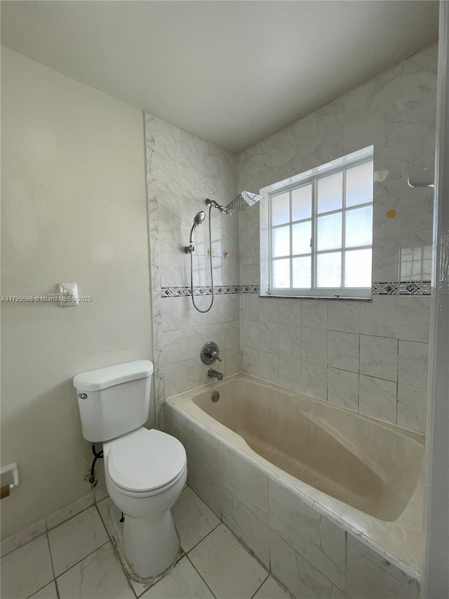 bathroom with tiled shower / bath combo and toilet