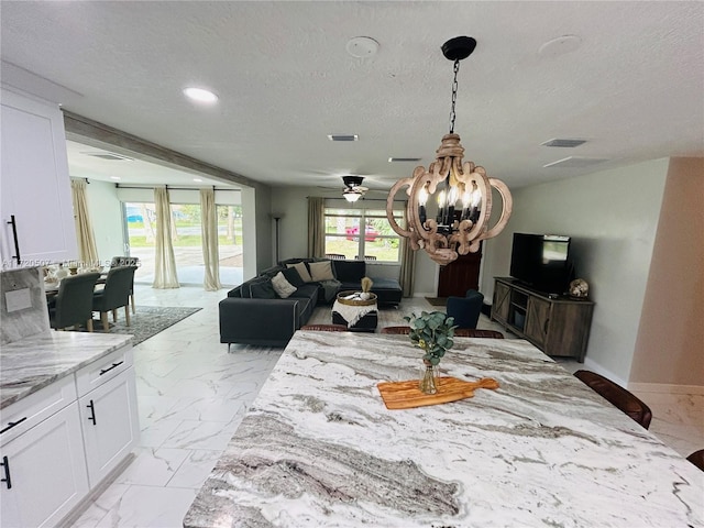 dining room with ceiling fan with notable chandelier and a textured ceiling