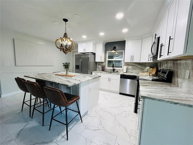 kitchen with white cabinetry, a center island, hanging light fixtures, a kitchen breakfast bar, and appliances with stainless steel finishes