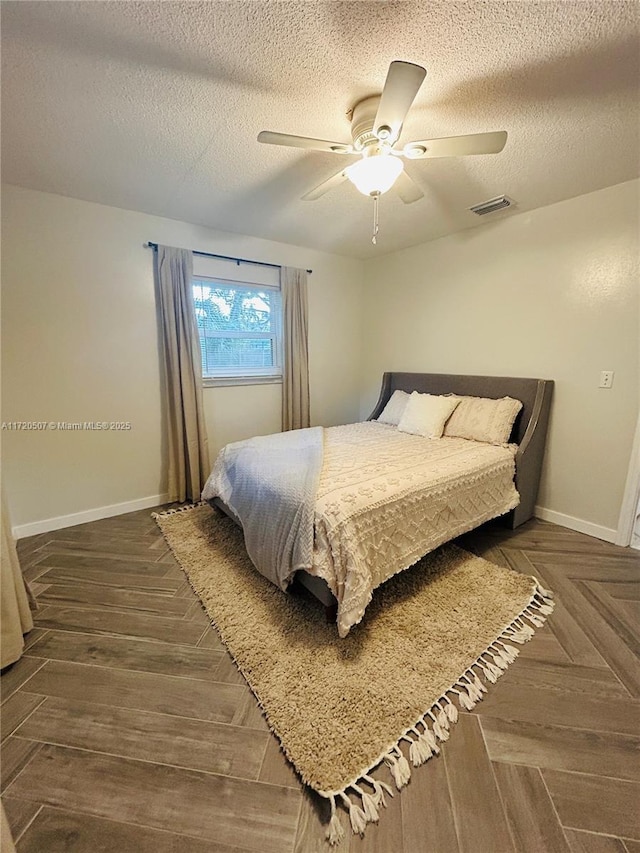 bedroom with dark parquet flooring, a textured ceiling, and ceiling fan