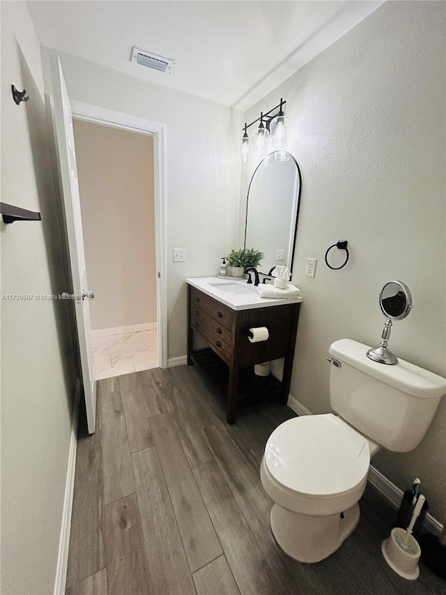 bathroom featuring vanity, hardwood / wood-style flooring, and toilet