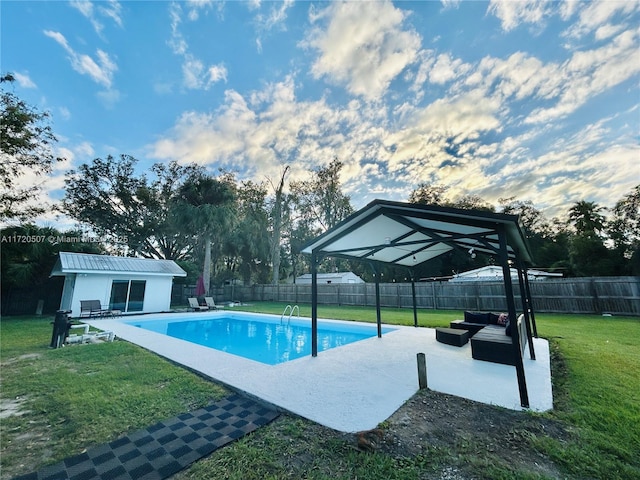 view of swimming pool featuring a lawn, an outdoor hangout area, and an outdoor structure