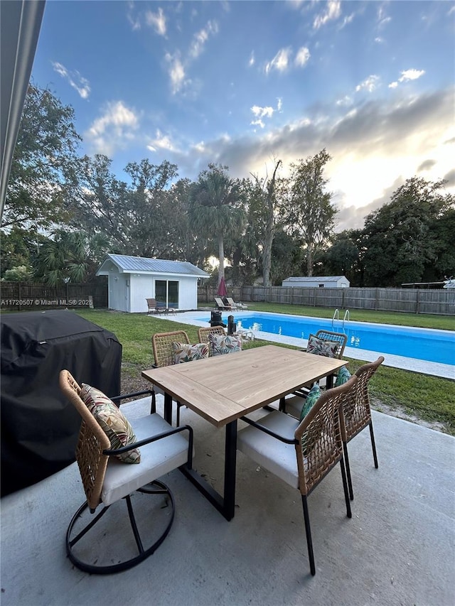 view of patio / terrace with a fenced in pool, grilling area, and an outbuilding