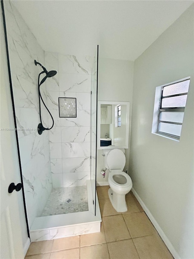 bathroom with a tile shower, tile patterned floors, and toilet