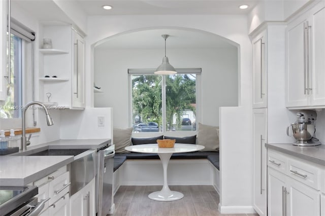 kitchen with white cabinetry, dishwasher, breakfast area, light hardwood / wood-style floors, and decorative light fixtures