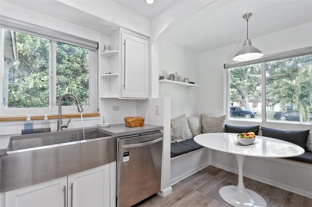 kitchen with dishwasher, sink, breakfast area, pendant lighting, and white cabinets