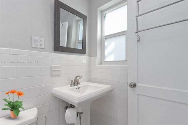 bathroom featuring toilet and tile walls