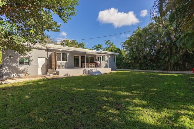 back of house featuring a lawn and a patio