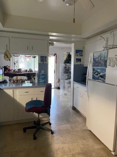 kitchen featuring white cabinets, ceiling fan, white fridge, and a tray ceiling